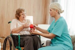 A nurse supports a senior woman with a stress ball promoting recovery and mobility.